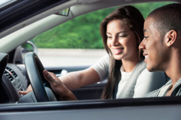 Man driving with woman driving instructor. Driving school qualifications concept image.