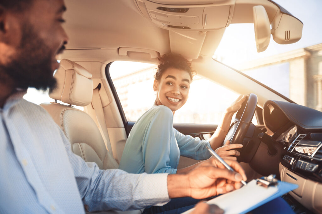 benefits of driving school, concept image. Young teen learning to drive in car with her drivng instructor.