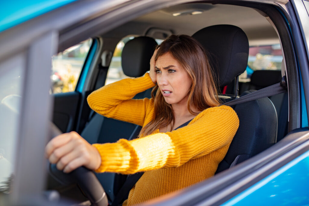 young woman driving in car seems anxious. Driving anxiety, concept image.